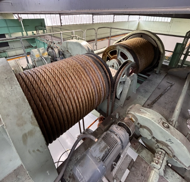 Dual crane hoist drums with steel wire rope and motor assembly in industrial overhead lifting system